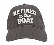 Load image into Gallery viewer, A dark gray baseball cap with &quot;RETIRED to the BOAT&quot; embroidered in bold, raised white letters on the front, highlighting a leisurely nautical lifestyle.