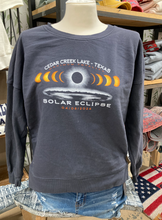 Load image into Gallery viewer, A mannequin models a charcoal gray fleece crewneck sweatshirt with a &quot;CEDAR CREEK LAKE - TEXAS SOLAR ECLIPSE 04/08/2024&quot; design, showcased in a rustic store setting.