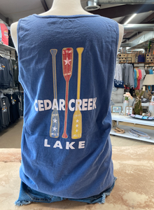 Rear view of a pacific blue tank top featuring 'Cedar Creek Lake' and crossed oar graphics, on a mannequin against a store backdrop.